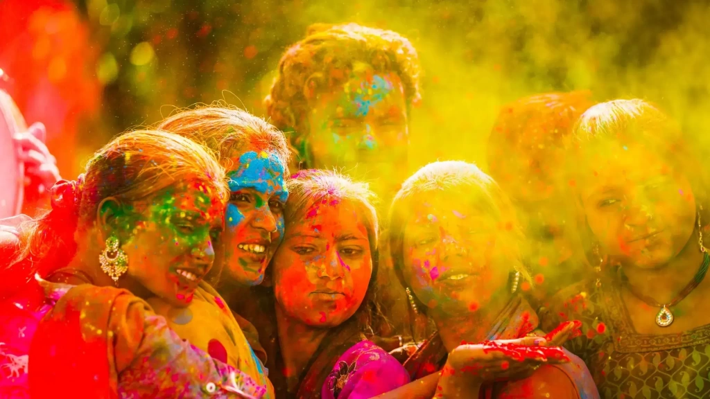 Friends joyfully celebrate with vibrant colored powder clouds during Holi, smiling together amid golden haze.