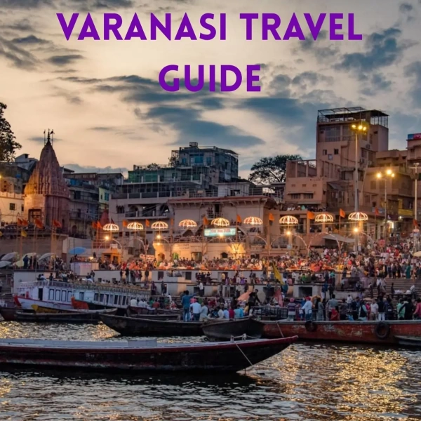 Evening view of Varanasi ghats with illuminated temples, crowded steps, and boats on the Ganges.