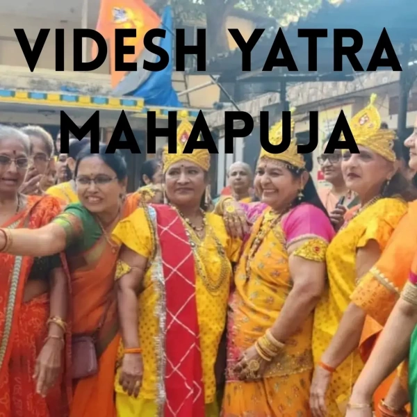 Women in vibrant yellow and orange traditional attire gather smiling during Videsh Yatra Mahapuja celebration.
